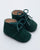 Green baby shoes with laces on a light gray background