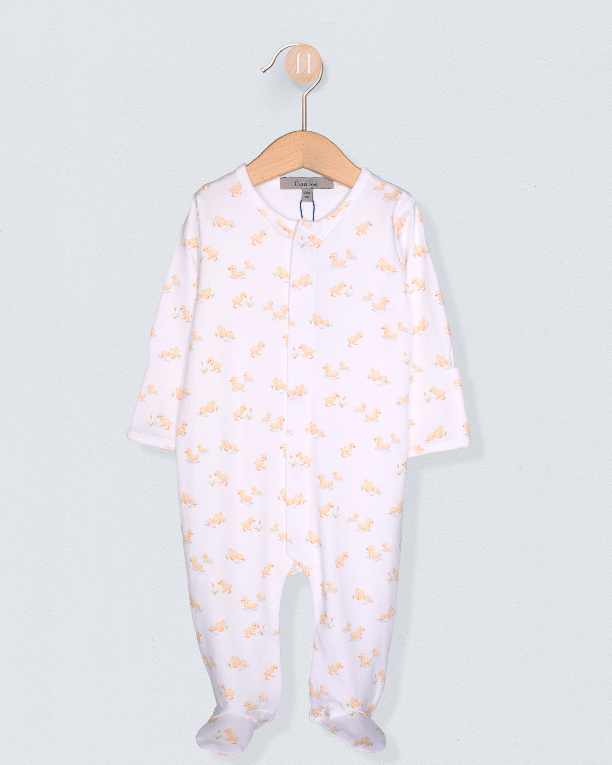 Baby onesie with yellow patterns on a hanger against a light gray background