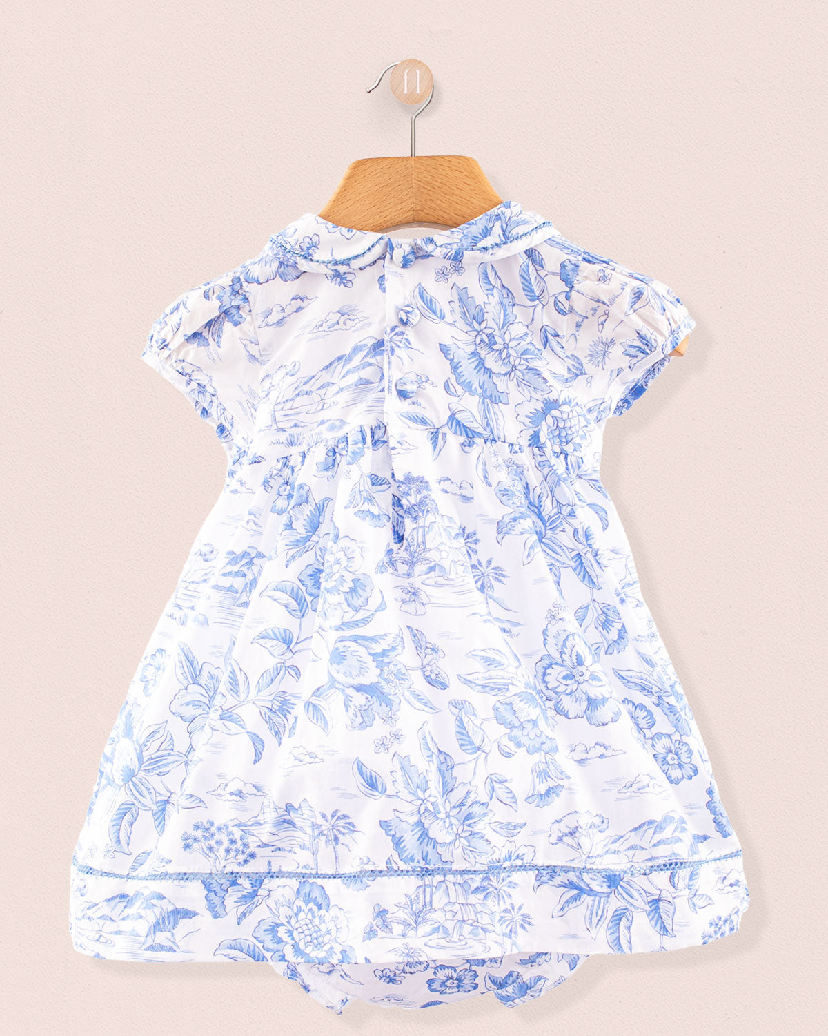 Back view of the Baby Emmy Liberty Delft Blue Dress showing two small back buttons, gentle gathering at the waist, and a matching printed diaper cover peeking underneath the skirt.