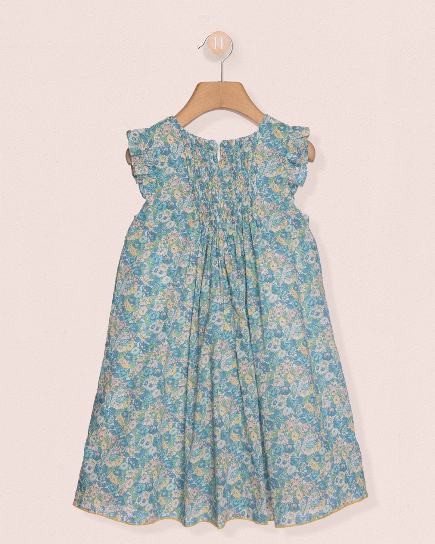 Blue floral dress on a hanger against a white background