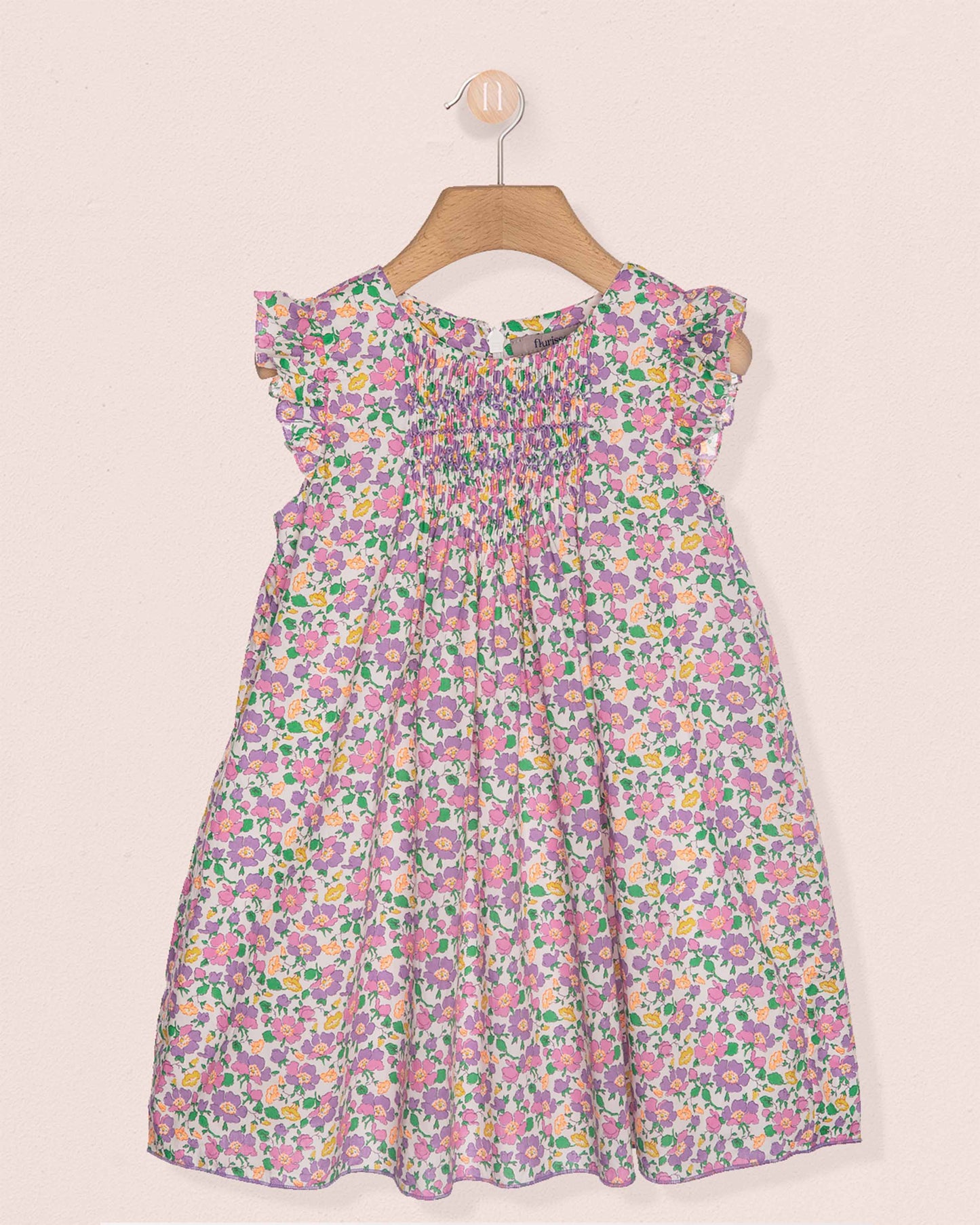Floral dress on a hanger against a light pink background