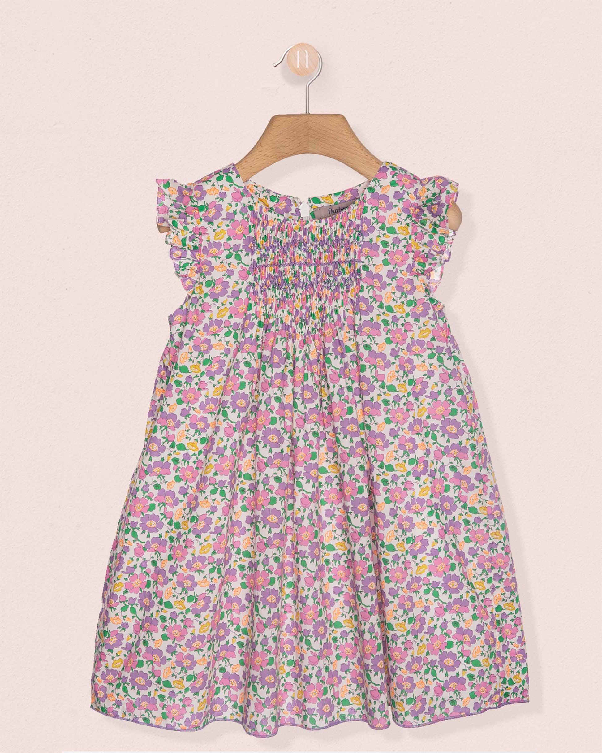 Floral dress on a hanger against a light pink background
