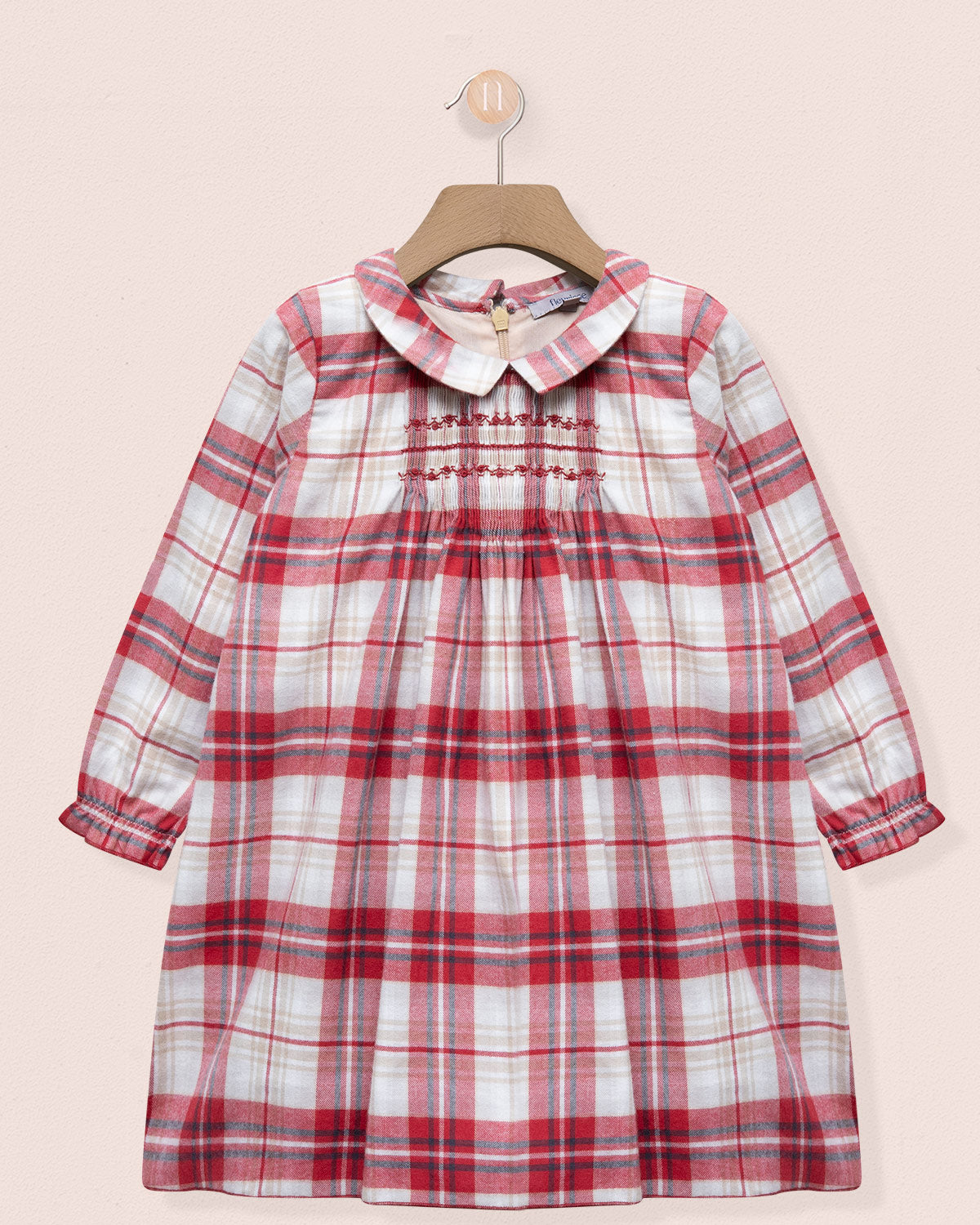 Red and white plaid dress on a hanger against a pink background