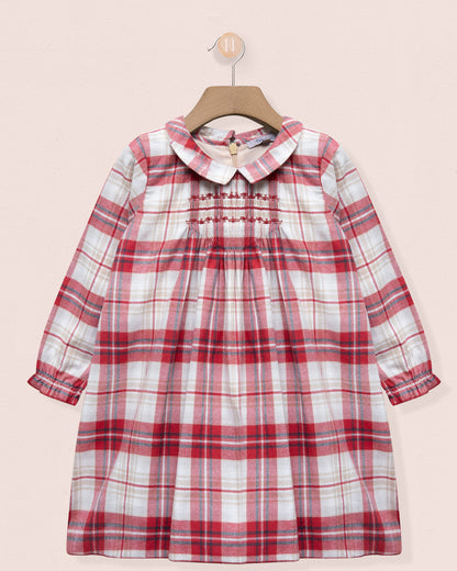 Red and white plaid dress on a hanger against a pink background