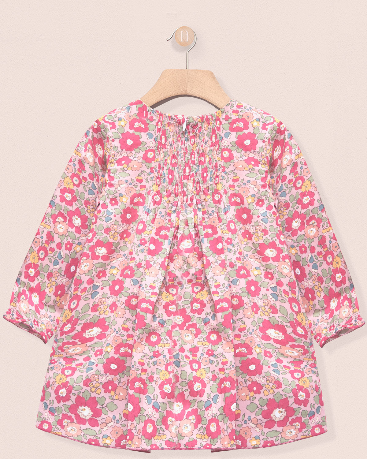 Floral patterned dress on a hanger against a beige background