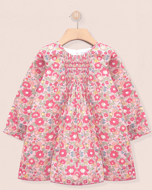 Floral dress on a hanger against a beige background