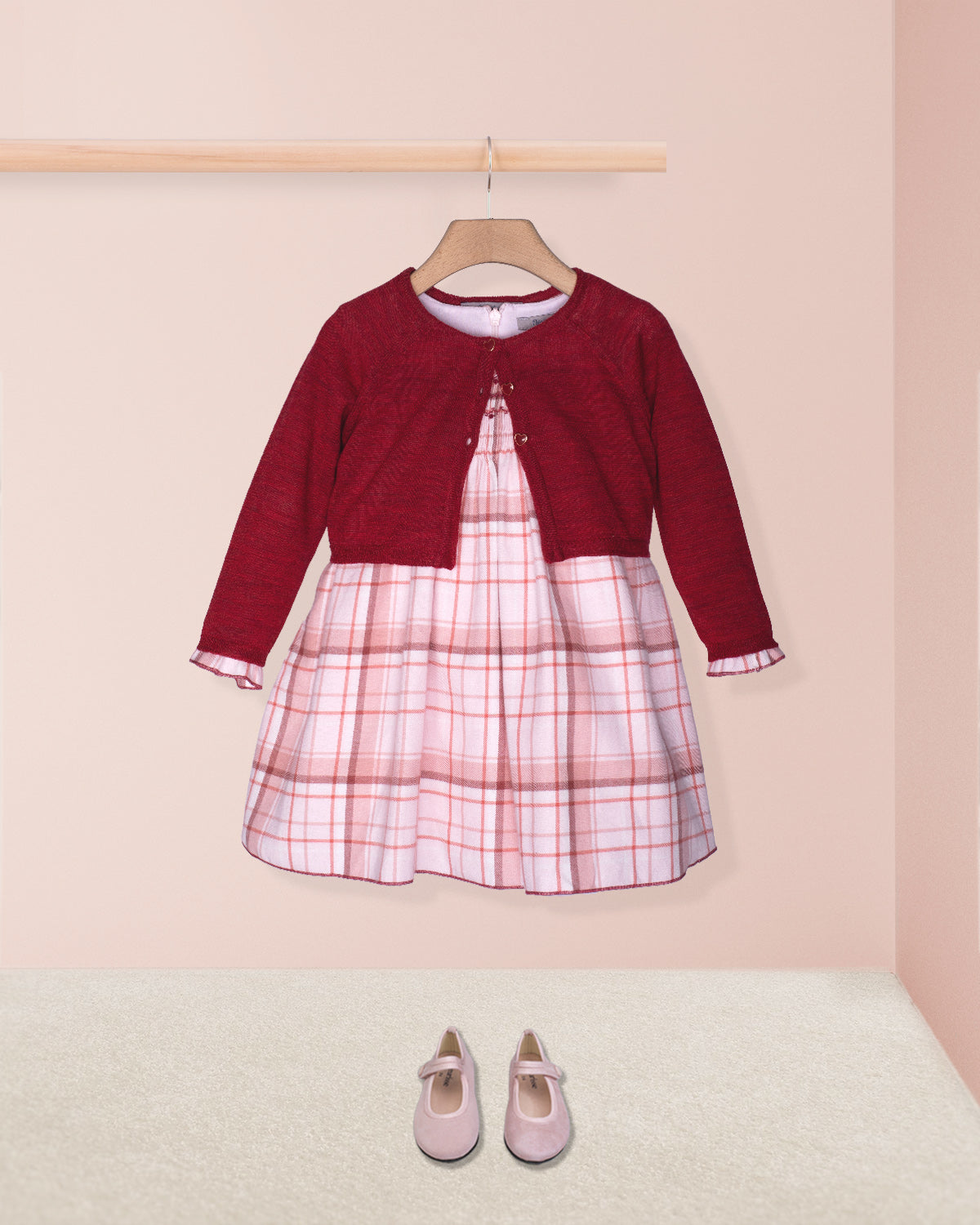 Red cardigan over a plaid dress with pink shoes on a beige background