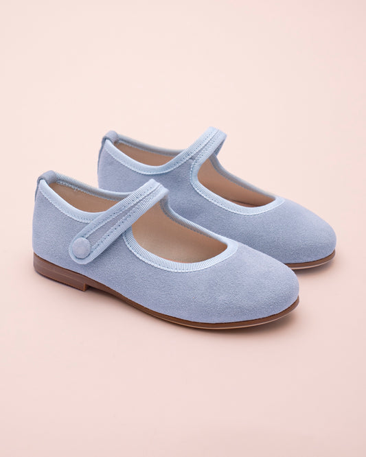 Pair of light blue children's shoes with a strap on a beige background