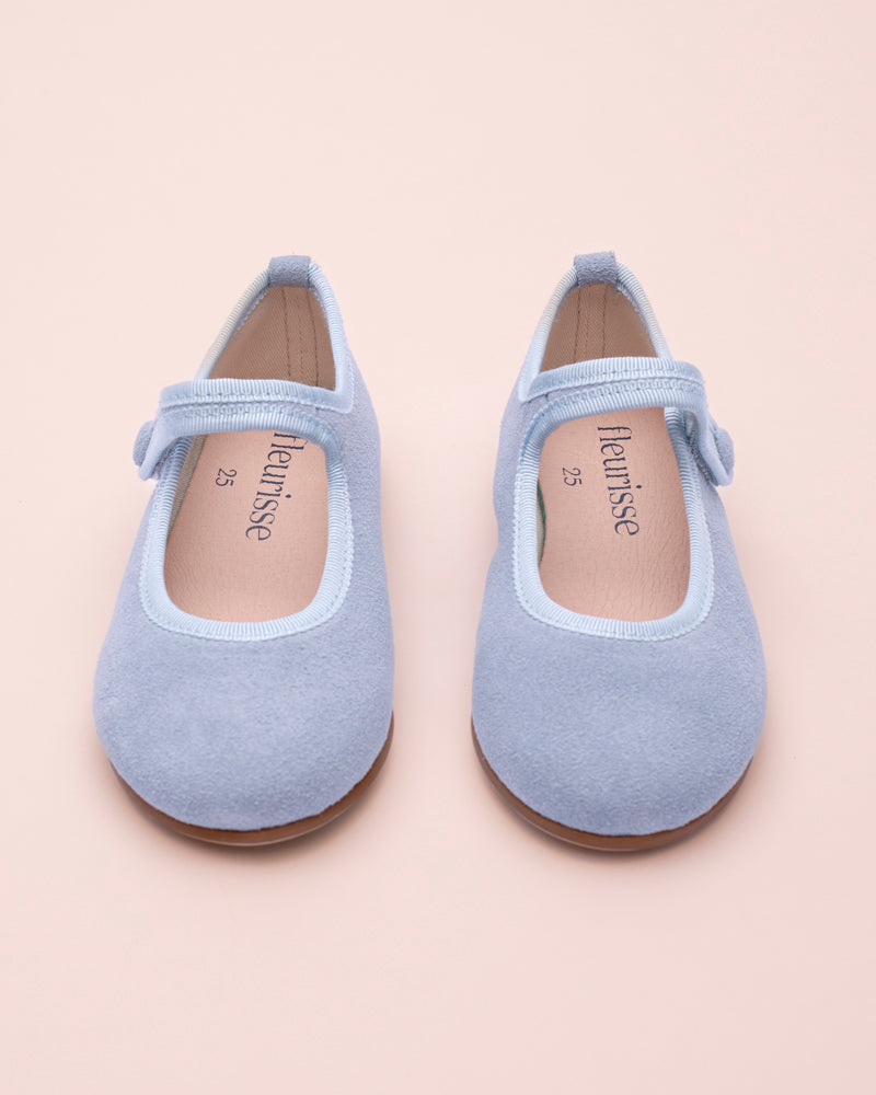 Pair of light blue children's shoes front view on a beige background