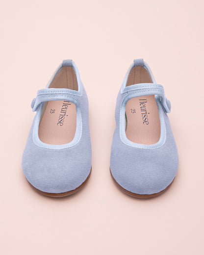 Pair of light blue children's shoes front view on a beige background