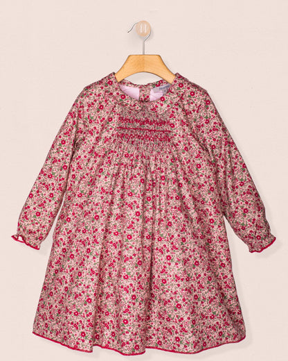 Front view of the Elizabeth Mini Mauve Floral Twill Dress hanging on a wooden hanger, showcasing its hand-smocked bodice, soft collar, and delicate mauve floral print.