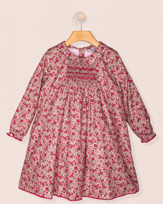 Front view of the Elizabeth Mini Mauve Floral Twill Dress hanging on a wooden hanger, showcasing its hand-smocked bodice, soft collar, and delicate mauve floral print.