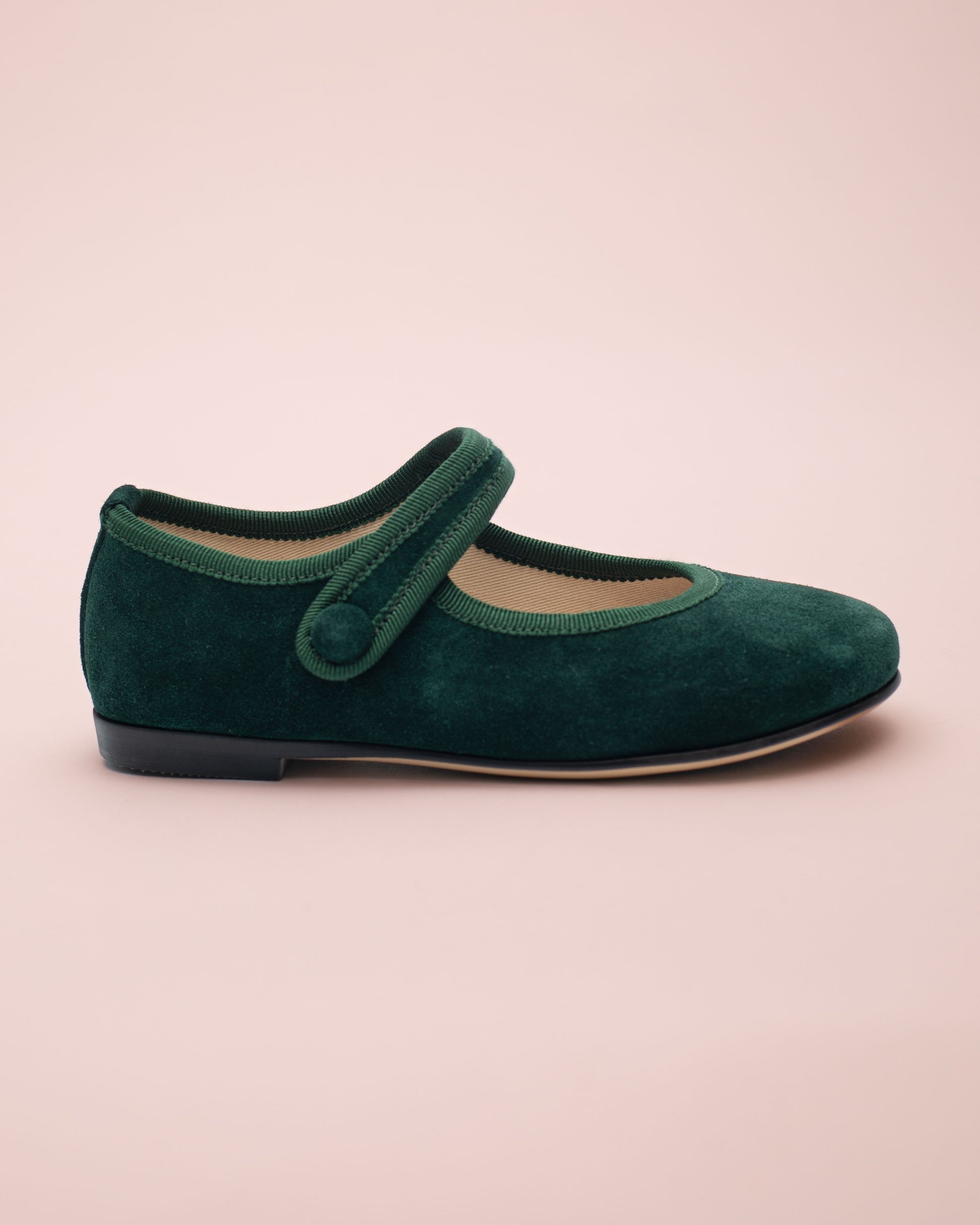 Green suede shoe with a strap on a beige background
