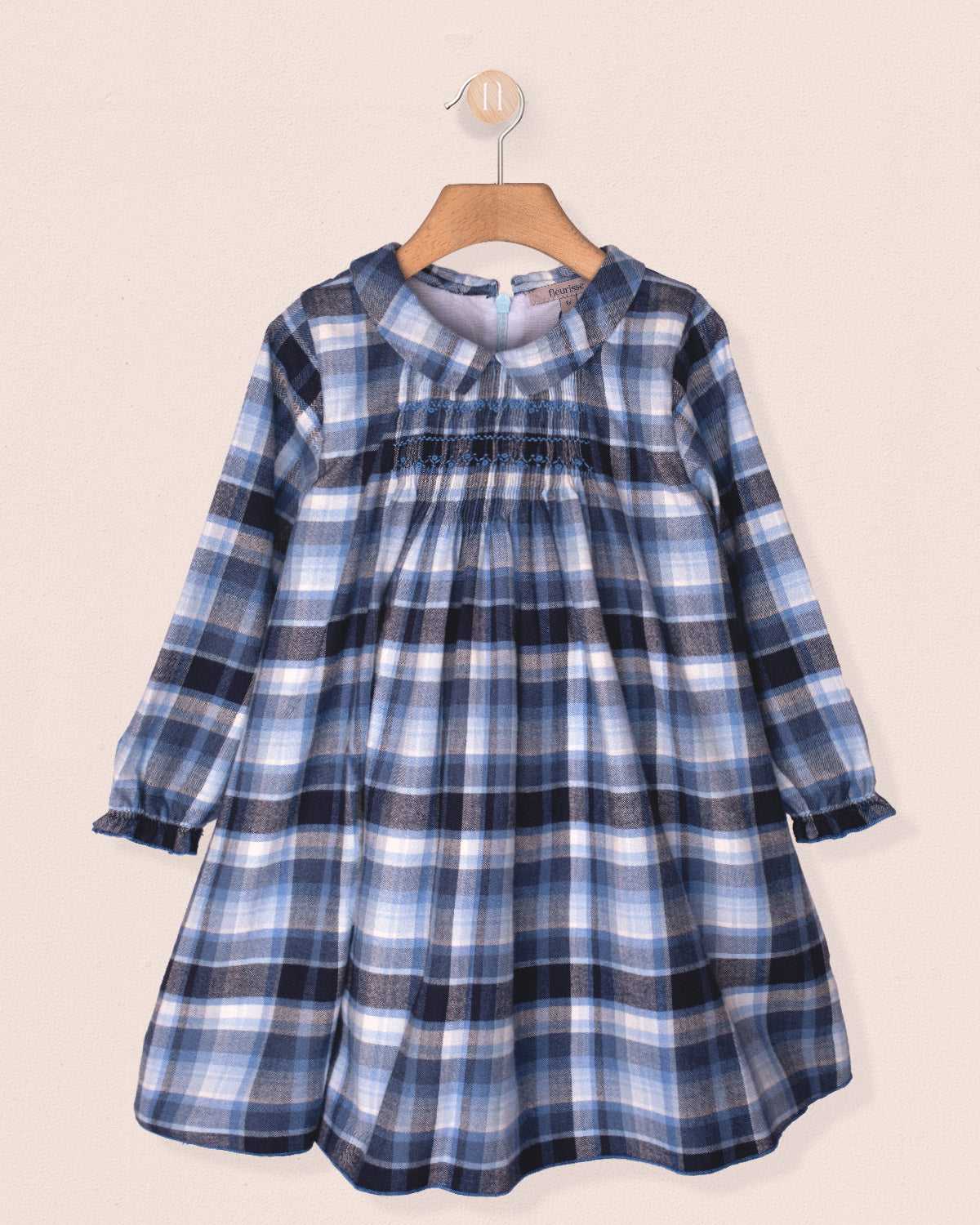 Blue plaid dress on a hanger against a beige background