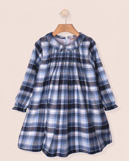 Blue plaid dress on a hanger against a beige background