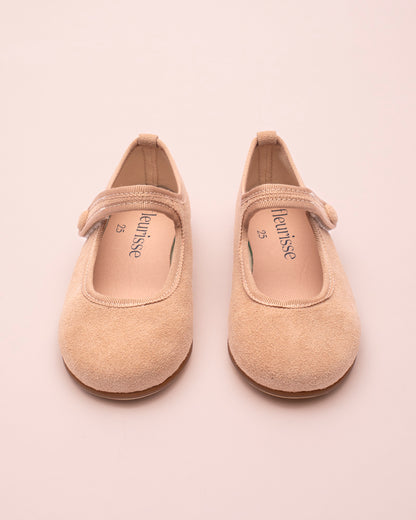 Pair of beige suede children's shoes with on a light pink background