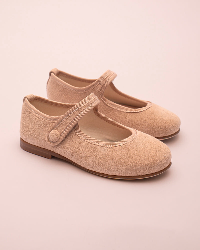 Pair of beige children's shoes with a strap on a light beige background