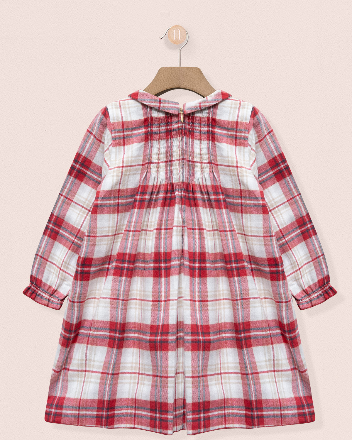 Red and white plaid dress on a hanger against a light pink background