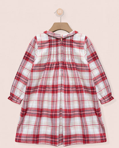 Red and white plaid dress on a hanger against a light pink background