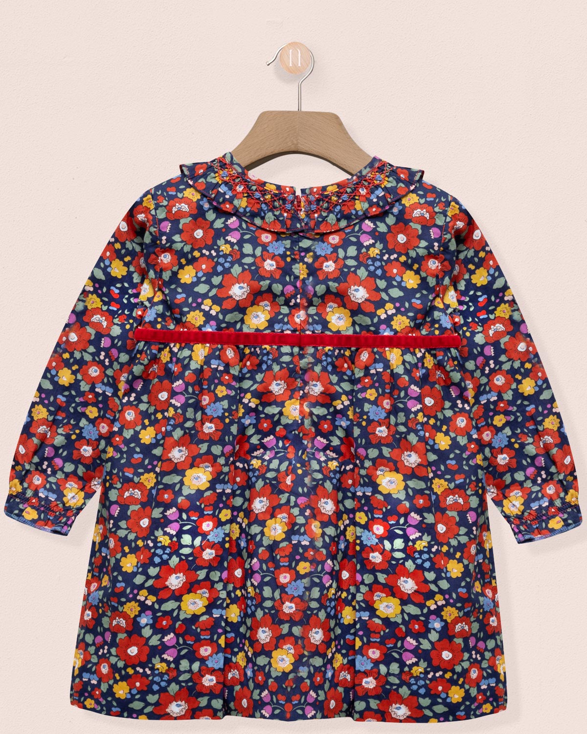 Children's floral dress on a hanger against a beige background