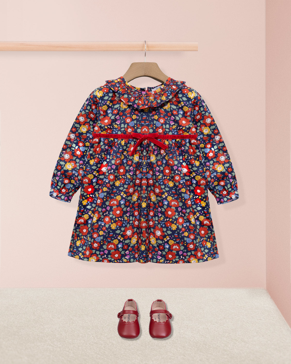 Floral dress with a red belt and matching shoes on a pink background