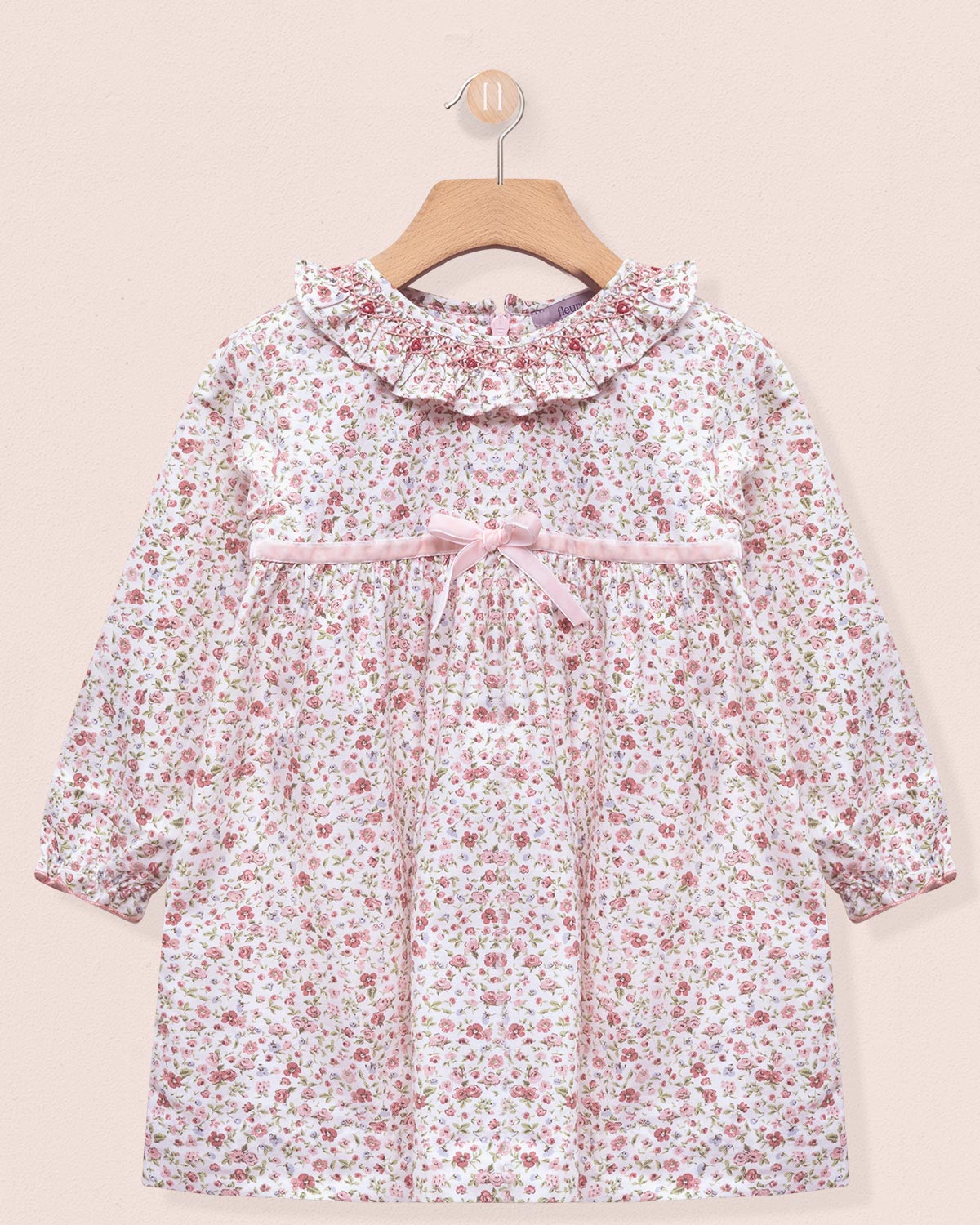 Floral dress on a hanger against a beige background