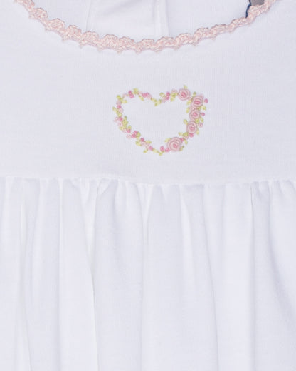 White gown with floral heart design and lace trim on a white background