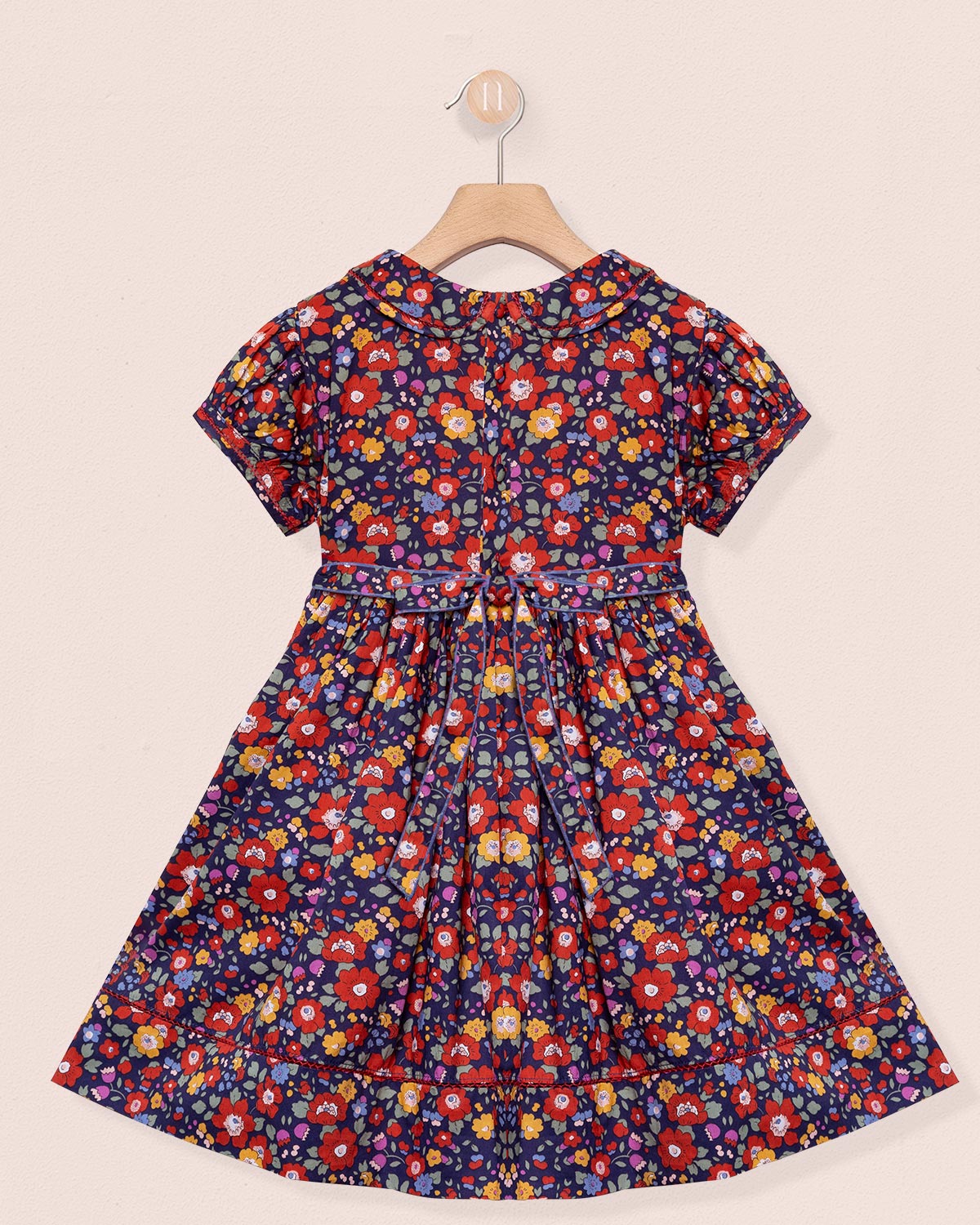 Floral dress on a hanger against a beige background