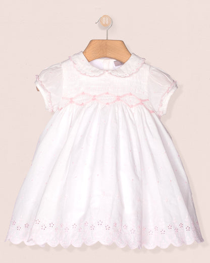 White dress with pink embroidery on a beige background