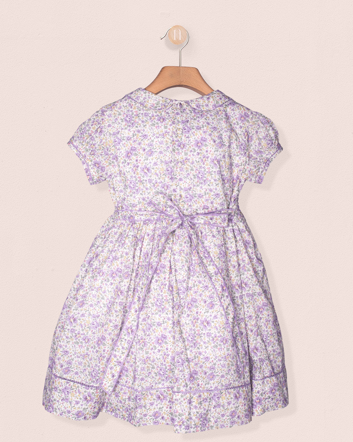 Floral dress on a hanger against a beige background
