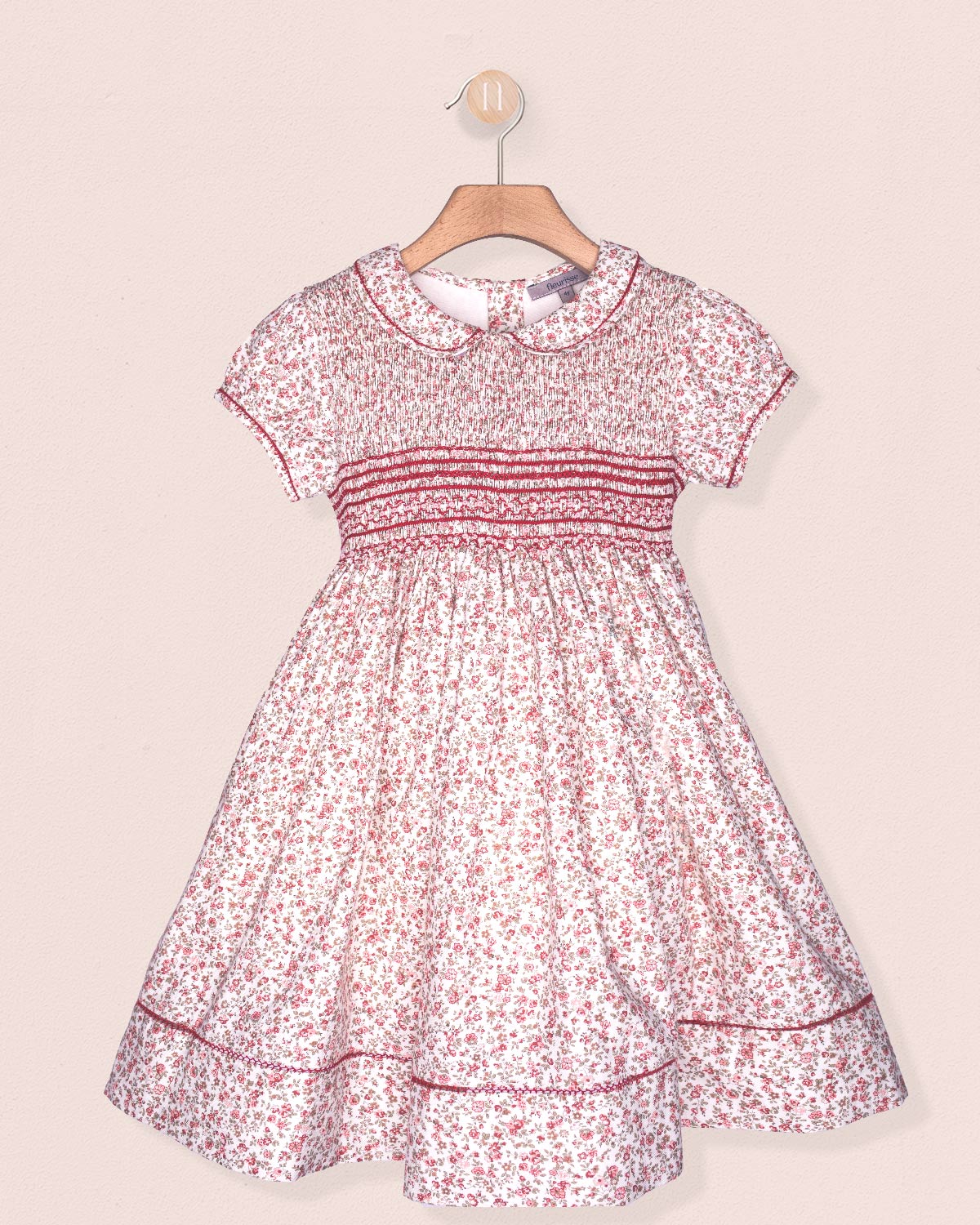 Floral dress on a hanger against a light pink background