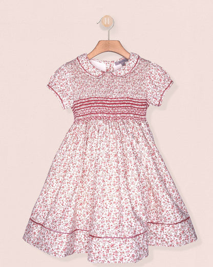 Floral dress on a hanger against a light pink background