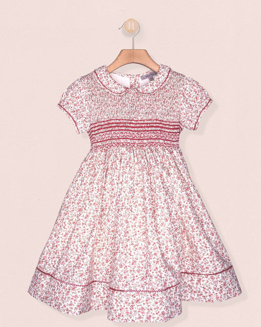 Floral dress on a hanger against a light pink background
