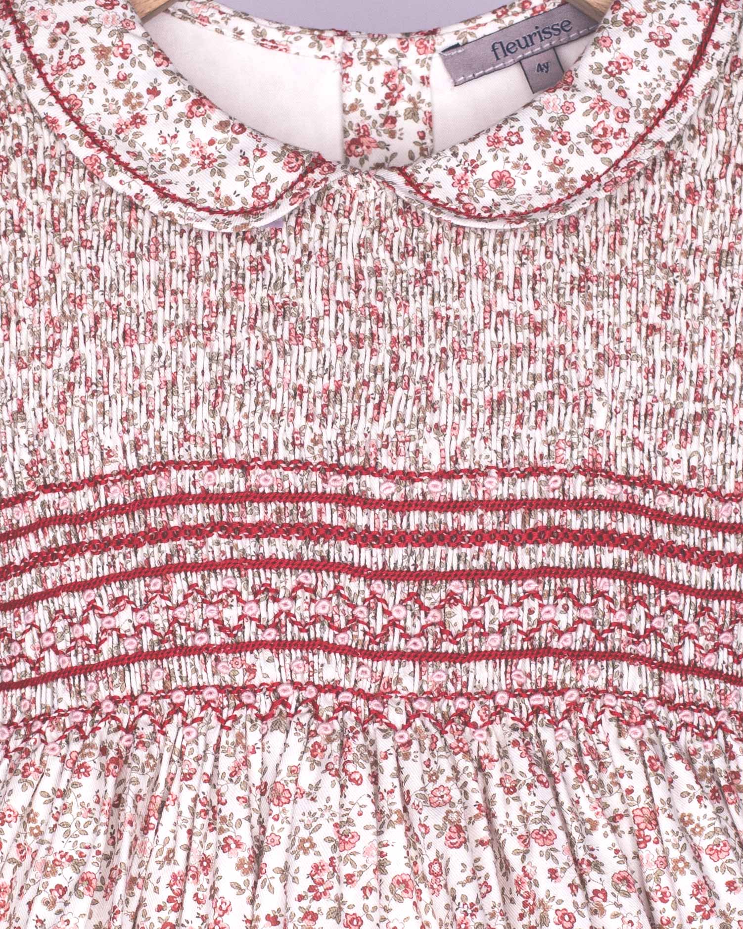 Close-up of a floral dress with smocked waistband and brand label.