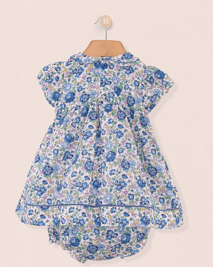 
Baby Emmy Liberty Blue Rosebud Mini Dress Set featuring a white dress with blue floral print, smocked bodice, Peter Pan collar, and matching floral bloomers.