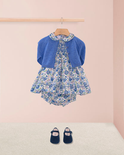 Baby Emmy Liberty Blue Rosebud Mini Dress Set, featuring a floral dress with smocked bodice and entre-deux stitching, paired with bloomers and a cerulean knitted cardigan.