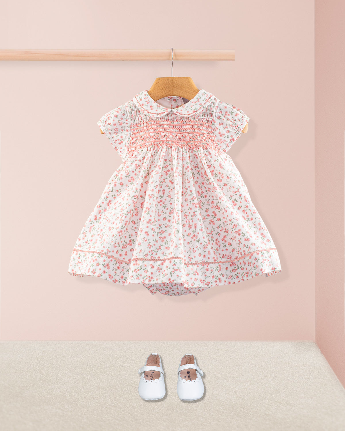 Full front view of the Baby Emmy Elegant Pink Floral Dress Set displayed with coordinating white baby shoes. Dress includes smocking, lace-trimmed hem, and a gathered full skirt.