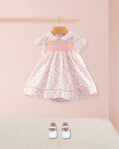 Full front view of the Baby Emmy Elegant Pink Floral Dress Set displayed with coordinating white baby shoes. Dress includes smocking, lace-trimmed hem, and a gathered full skirt.