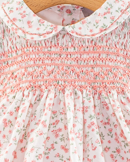 Close-up of the smocked bodice and Peter Pan collar on the Baby Emmy Elegant Pink Floral Dress, showing detailed hand-smocking in petal pink thread and a small-scale floral pattern on white cotton fabric.