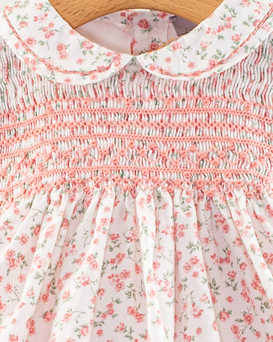 Close-up of the smocked bodice and Peter Pan collar on the Baby Emmy Elegant Pink Floral Dress, showing detailed hand-smocking in petal pink thread and a small-scale floral pattern on white cotton fabric.