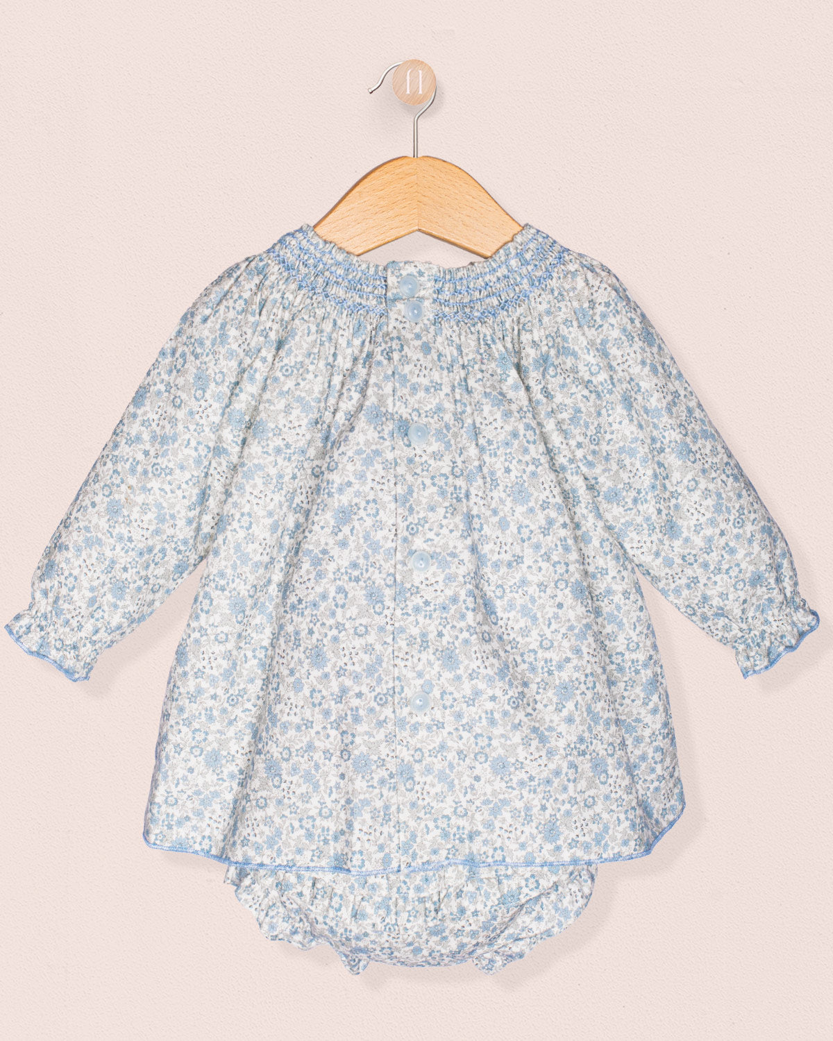 Baby dress with floral pattern on a hanger against a light background