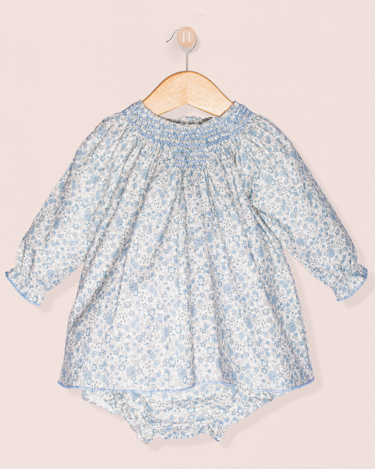 Baby dress with floral pattern on a hanger against a light background