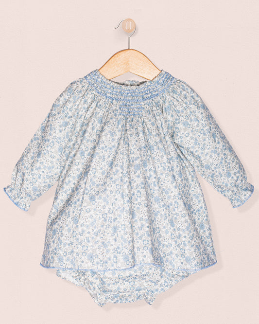 Baby dress with floral pattern on a hanger against a light background