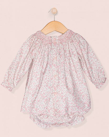Floral baby romper on a hanger against a light pink background