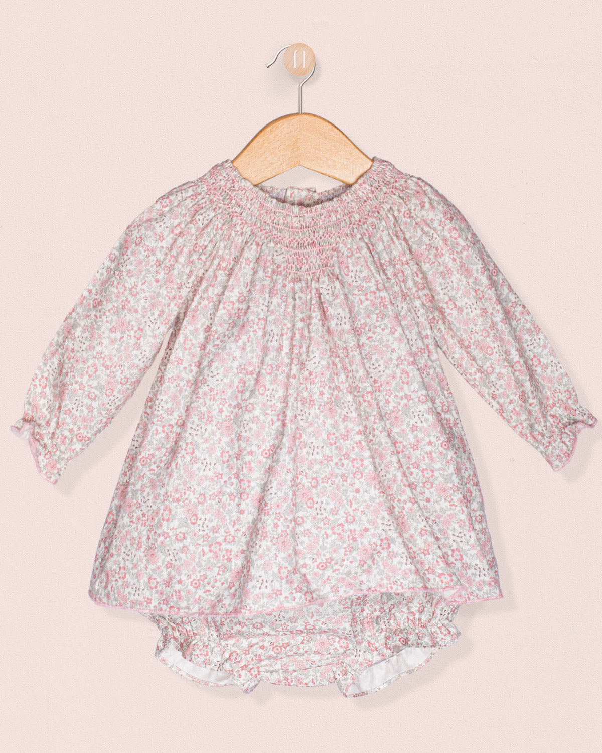 Floral dress on a hanger against a light pink background