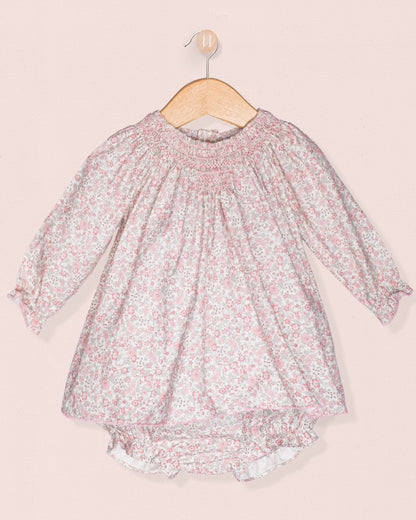 Floral dress on a hanger against a light pink background