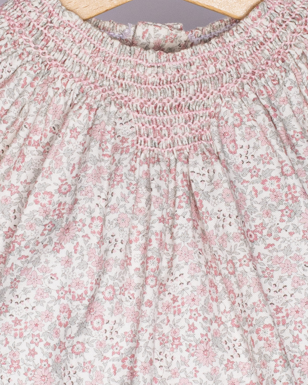 Close-up of a floral patterned fabric with pink and white flowers on a light background.