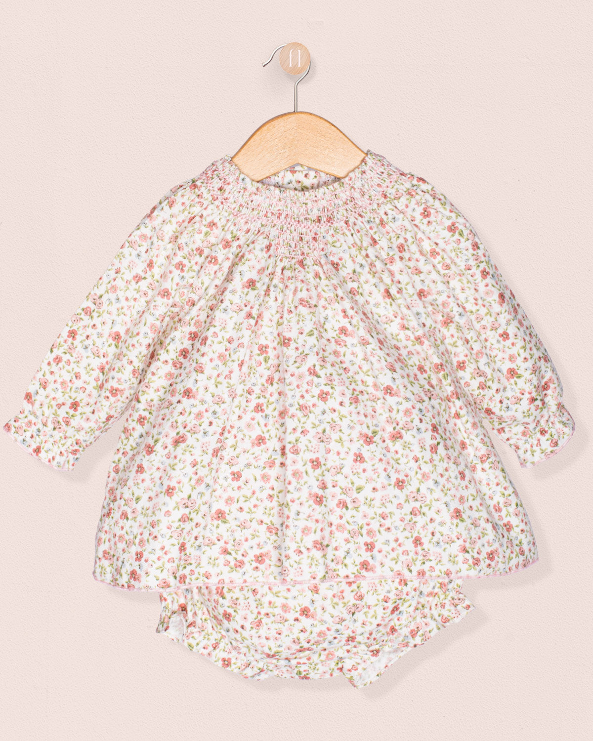 Floral dress on a hanger against a light pink background
