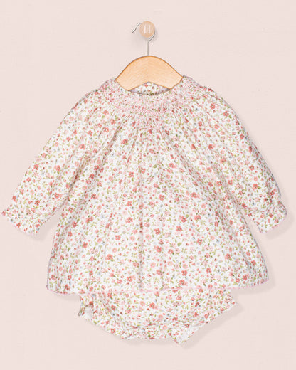 Floral dress on a hanger against a light pink background