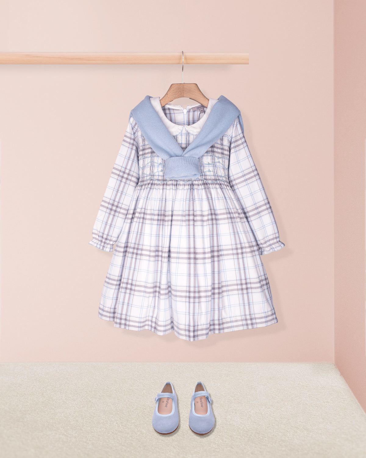 Children's plaid dress with blue collar and matching shoes on a pink background